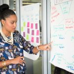 Professional woman presenting business strategy on paper in office. Engaged in workplace discussion.