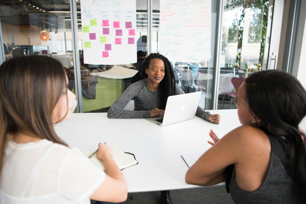 A diverse group of women collaborates around a desk in a modern office setting.