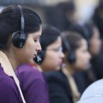 Call center agents wearing headsets working in a focused office environment.