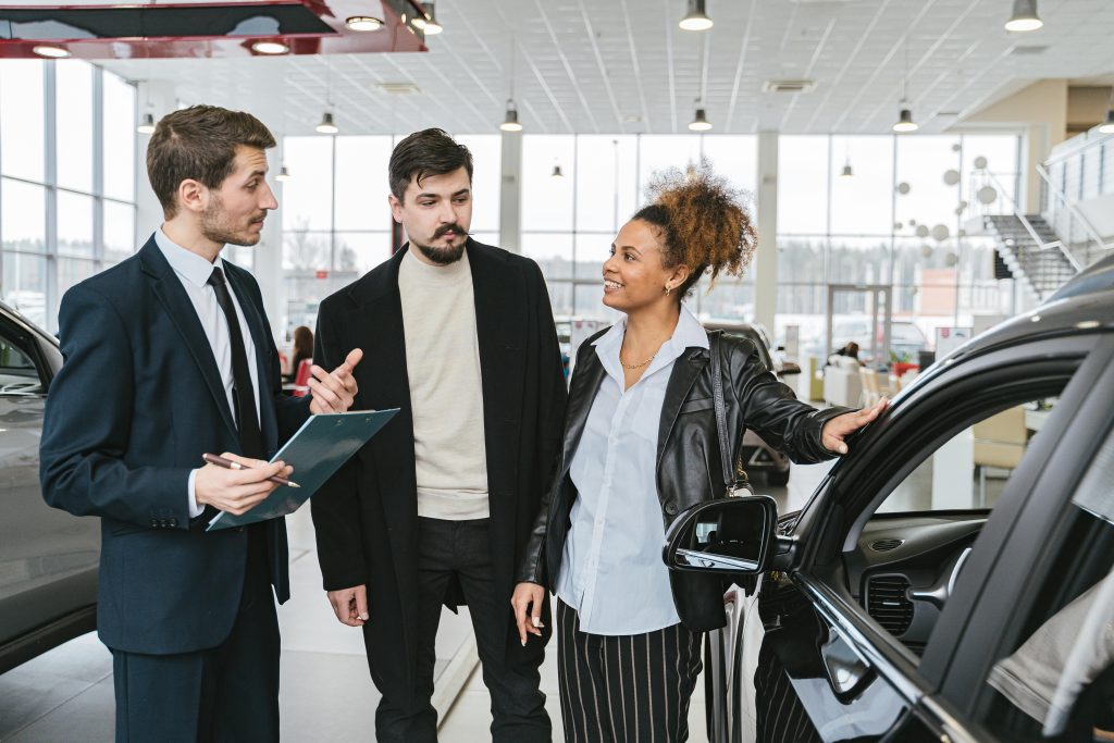 A diverse team of adults discussing a car purchase in a dealership showroom.