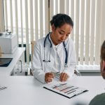 A doctor consulting with a patient in an office, discussing a medical chart.