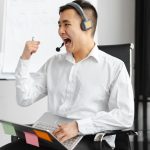 Asian call center agent in office celebrating a successful call with expressive gesture.