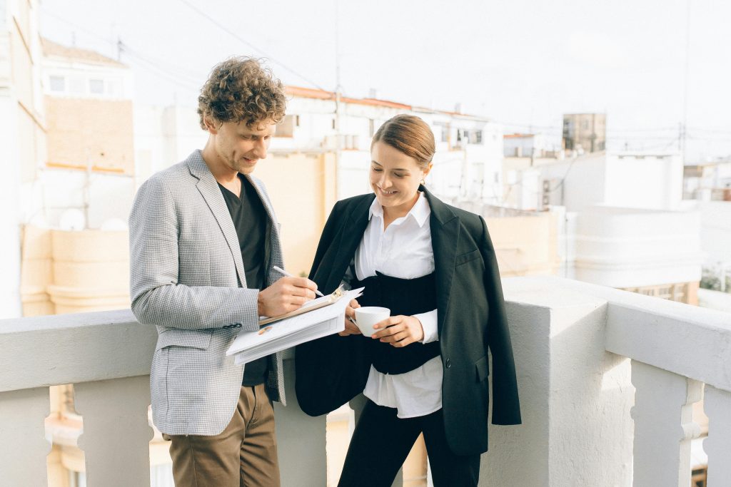 Two business professionals conversing on a rooftop, discussing strategies while enjoying a coffee break.