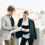 Two business professionals conversing on a rooftop, discussing strategies while enjoying a coffee break.