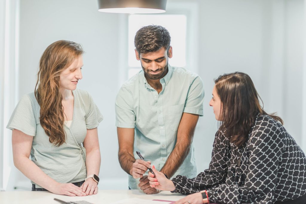 Three colleagues discussing a project in a bright office setting. Collaborative and friendly business environment.