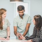 Three colleagues discussing a project in a bright office setting. Collaborative and friendly business environment.